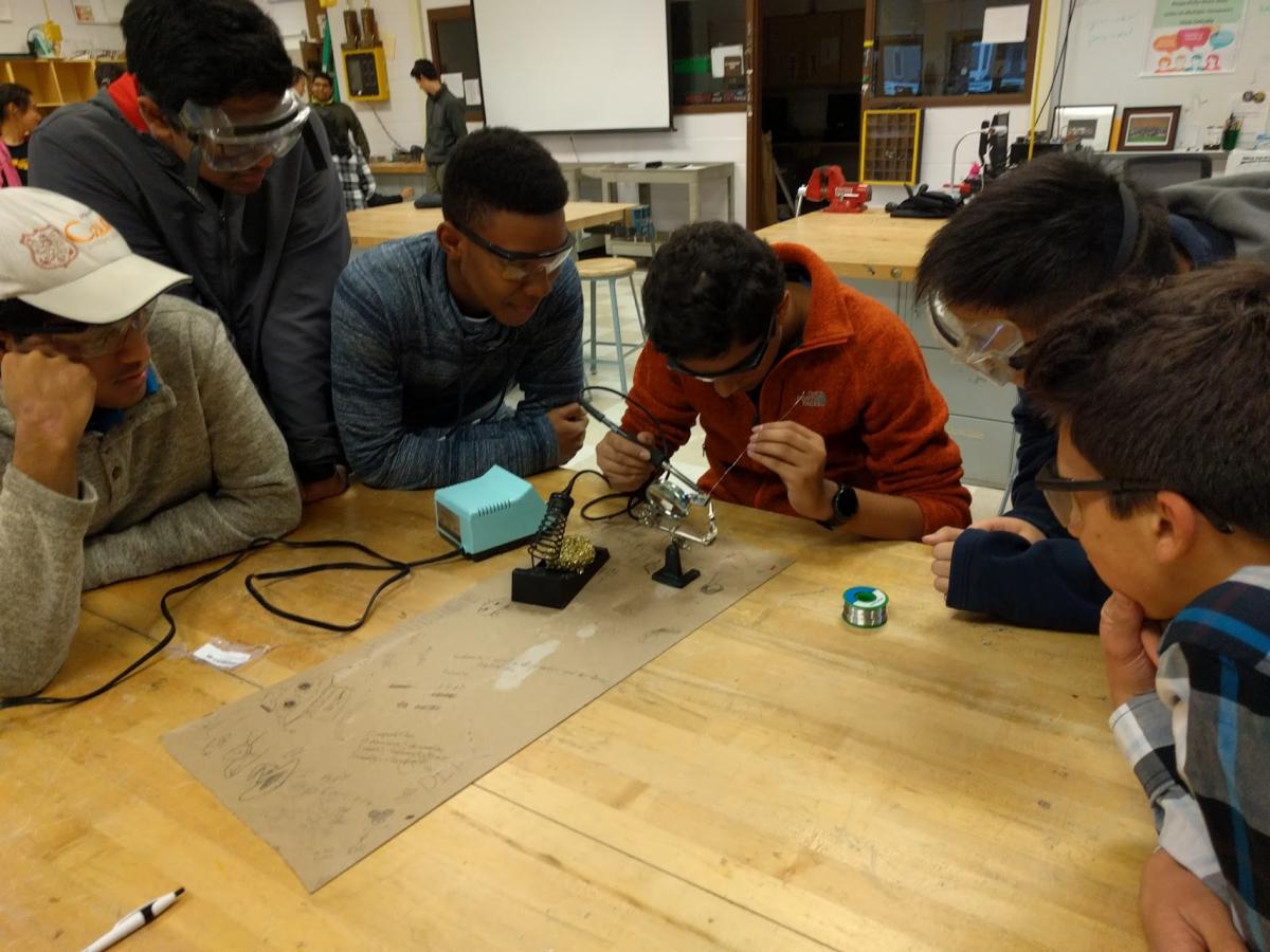 A group of students soldering 